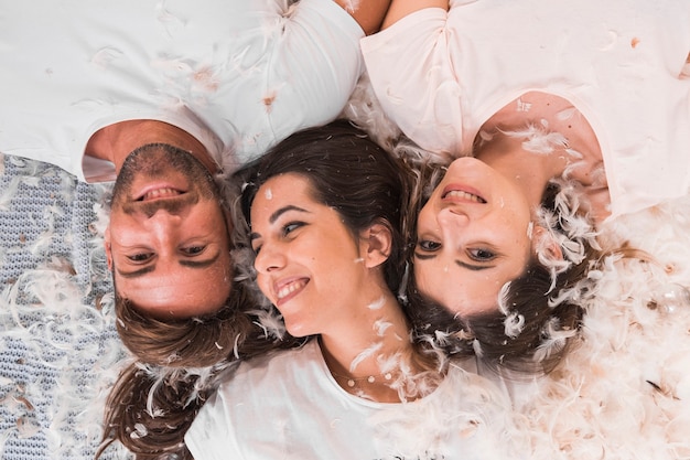 White feather over the friends lying on bed