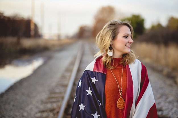 Free photo white female covered in the flag of the united states of america