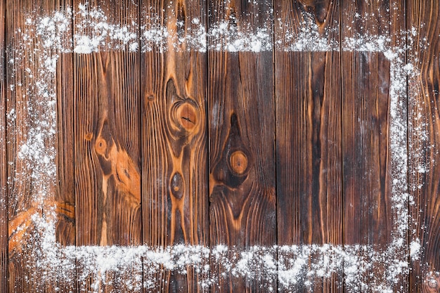 White flour over the edge of rectangular frame on wooden table