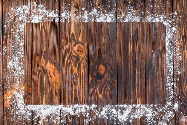 White flour over the edge of rectangular frame on wooden table