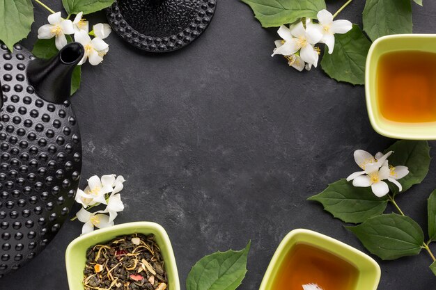 White flower and dry herb tea arranged in frame on black backdrop