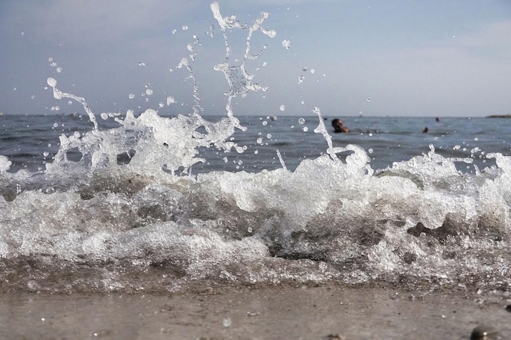 無料Photo 白い泡と海水の滴が砂と青い水とゆっくりとスプラッシュします