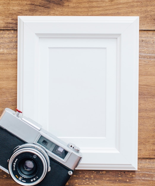 White frame on wooden background with old camera