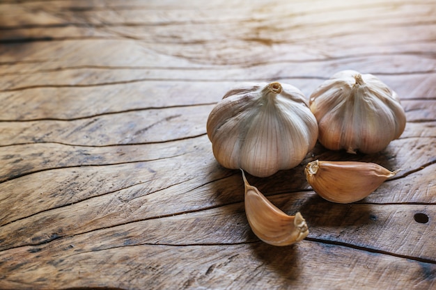 White garlic placed on a dark brown wood floor.