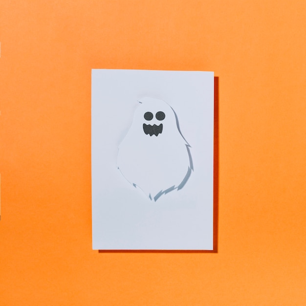 Fantasma bianco con faccia buffa su un foglio di carta
