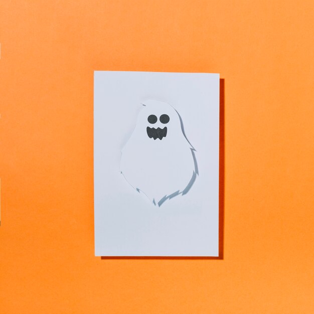 White ghost with funny face on sheet of paper