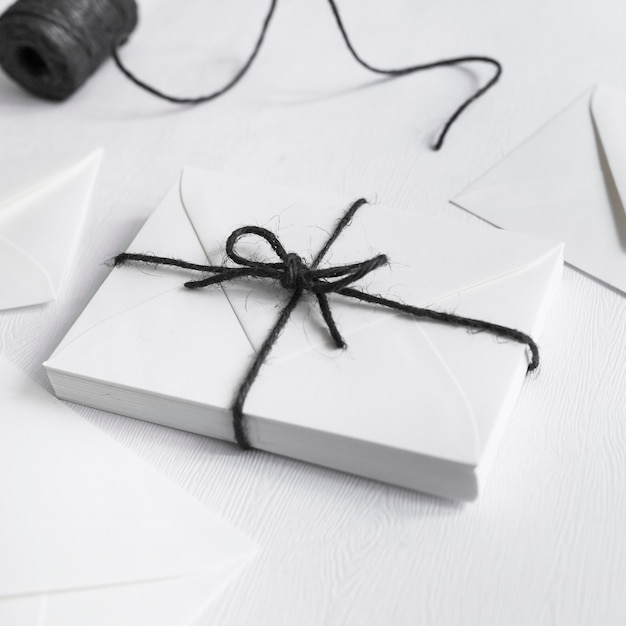 Белая подарочная коробка, связанная с черной струной на белом фоне