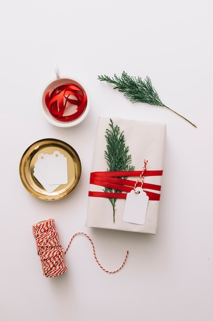 Free photo white gift box with tied cypress branch on table