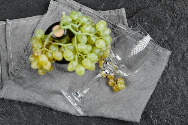 Бесплатное фото Белый виноград и бутылка вина на темной поверхности