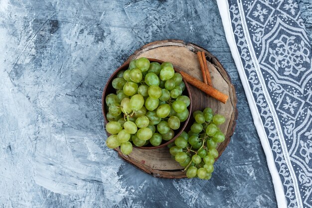 Uva bianca, cannella su una tavola di legno con carta da cucina vista dall'alto su uno sfondo di marmo blu scuro Foto Gratuite