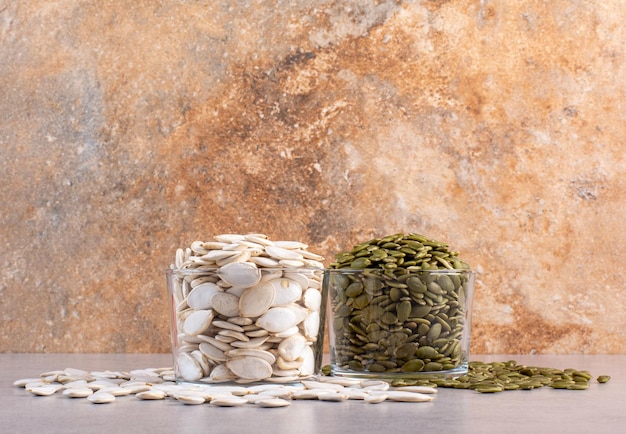 White and green pumpkin seeds on concrete background.