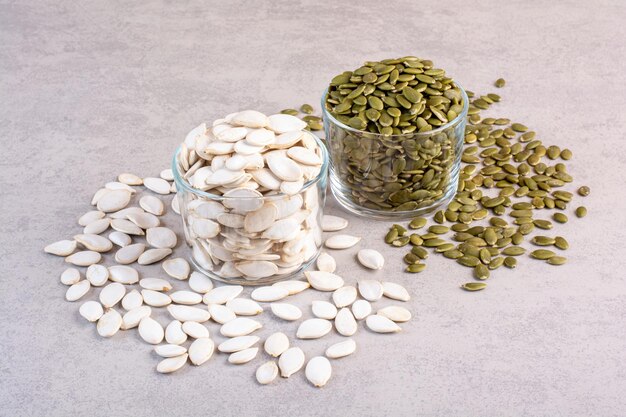 White and green pumpkin seeds on concrete surface.