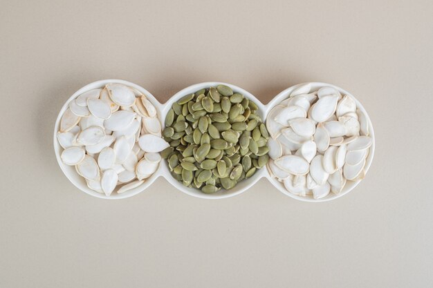 White and green pumpkin seeds in white cups.