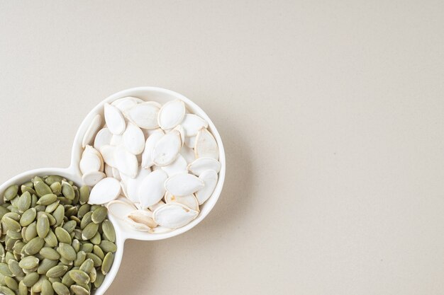 White and green pumpkin seeds in white cups.