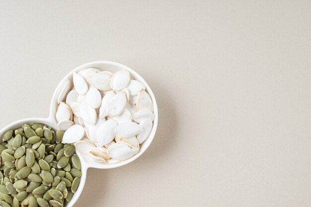 흰색 컵에 흰색과 녹색 호박 씨앗.