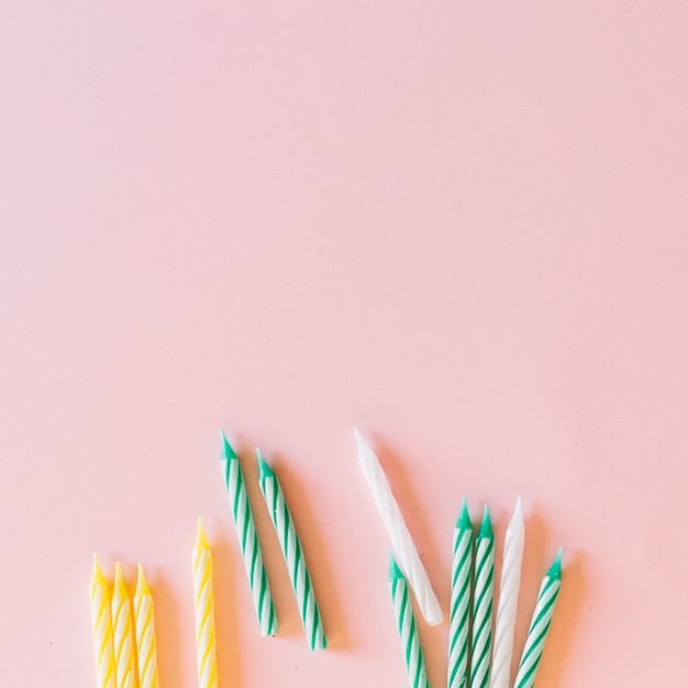 White; green and yellow stripes pattern candles on pink background