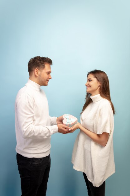 White heart. Beautiful couple in love on blue studio wall