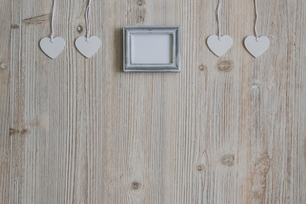 White hearts hanging on a rope and a blank photo frame in the middle