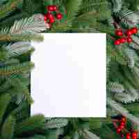 Free photo white invitation image with text on a background of fir tree branches and red balls