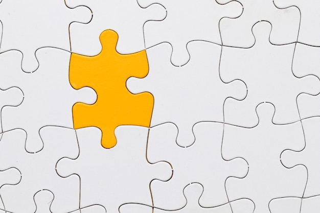 White jigsaw puzzle sheet with yellow puzzle piece in center