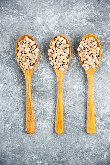 Foto gratuita fagioli bianchi in ciotola blu e cucchiai di legno.