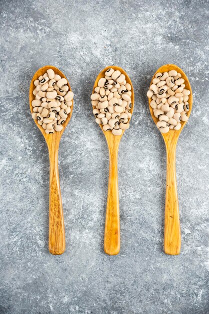 White kidney beans in blue bowl and wooden spoons.