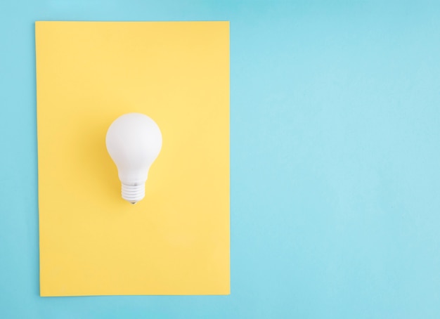 White light bulb on yellow paper over the blue background