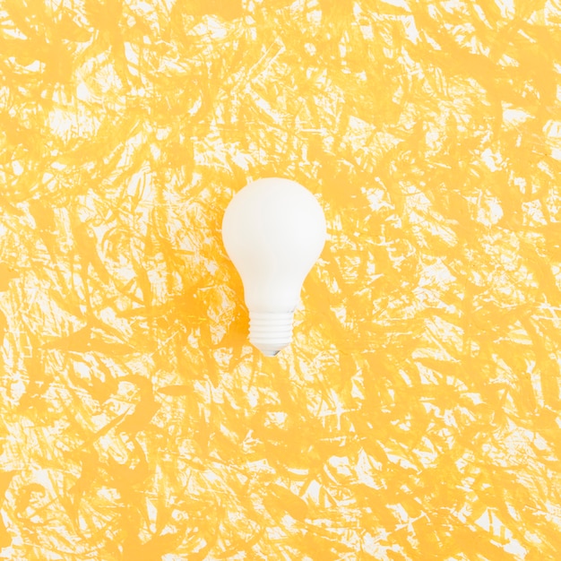 White light bulb on yellow textured backdrop