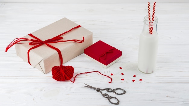 White liquid in bottle with tubes near little hearts, scissors and presents