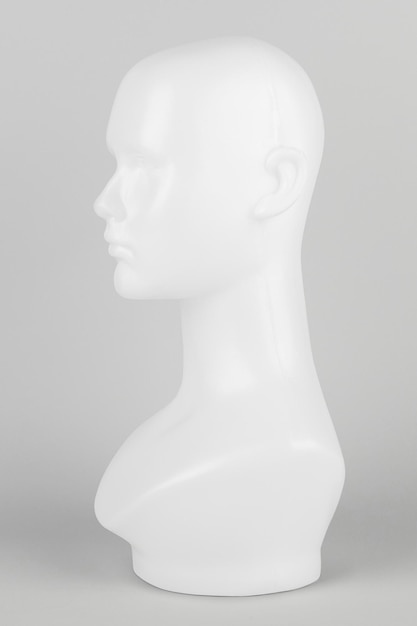 White mannequin head in profile on a gray background