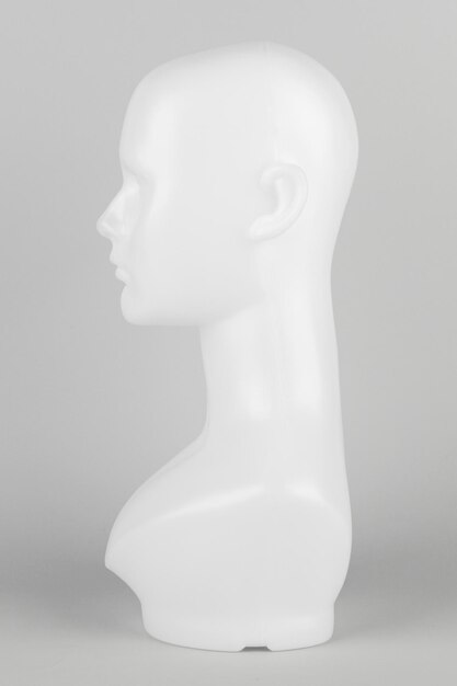 White mannequin head in profile on a gray background