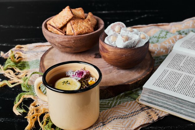 White marshmallows in a wooden cup with crackers and tea.