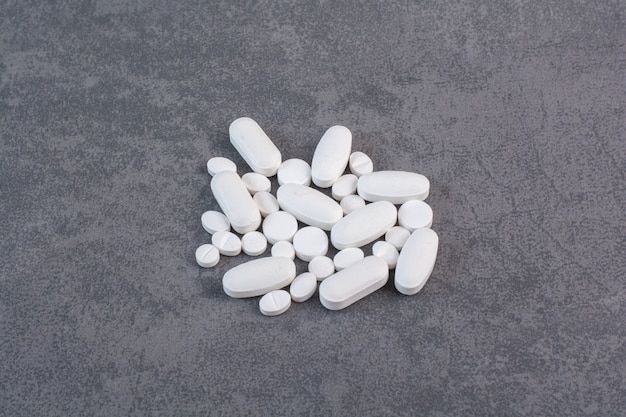 White medical pills on marble table.