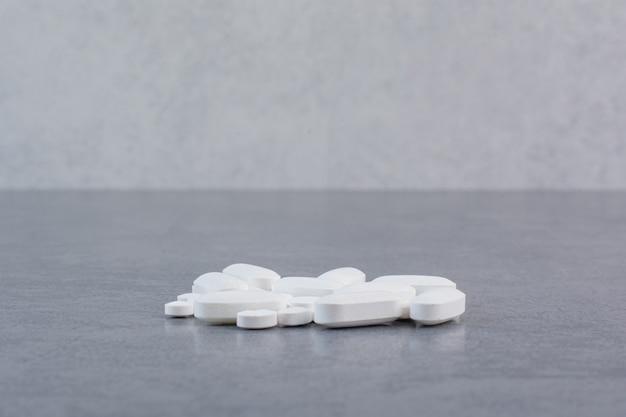 White medical pills on marble table.