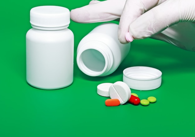 Белые бутылки медицины, цветные таблетки на цветном фоне.
