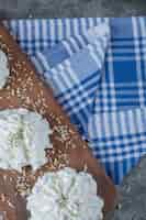 Free photo white meringue cookies with coconut powder on a wooden board on the blue towel.