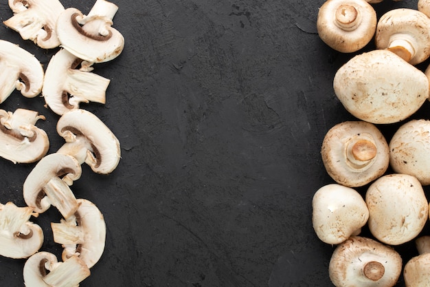 Free photo white mushrooms fresh sliced and ripe champignons on dark background