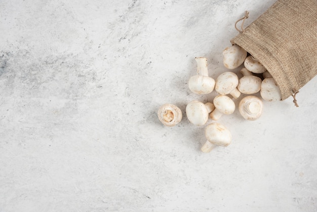 White mushrooms inside rustic baskets on marble table.