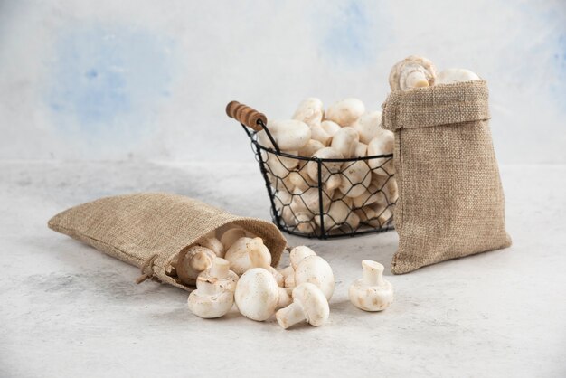 White mushrooms inside rustic baskets and a metallic tray.