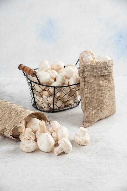 White mushrooms inside rustic baskets and a metallic tray.