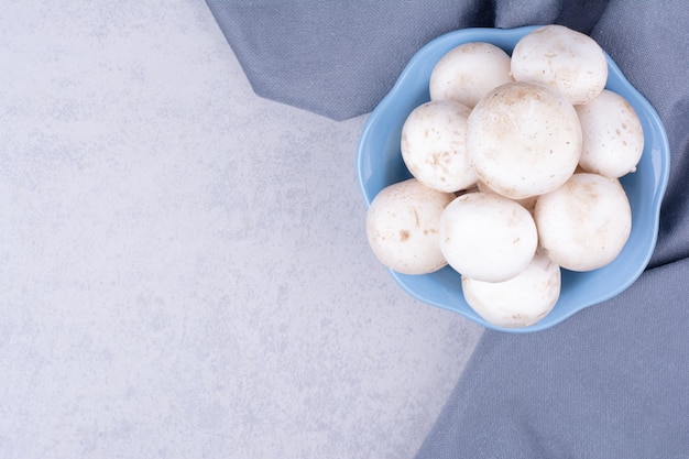 White mushrooms isolated in a blue bowl.