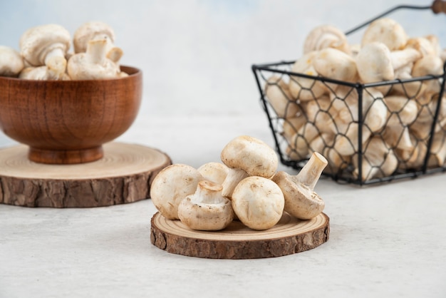 Белые грибы в металлической корзине, в деревянной чашке и на деревянной доске.