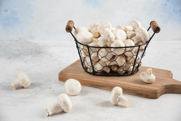 White mushrooms in a metallic tray on a wooden platter.