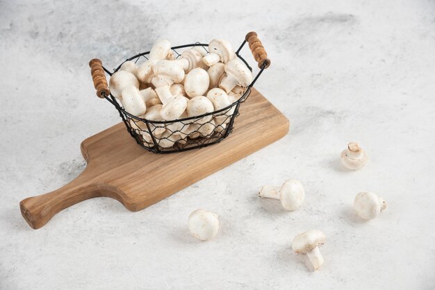 White mushrooms in a metallic tray on a wooden platter.