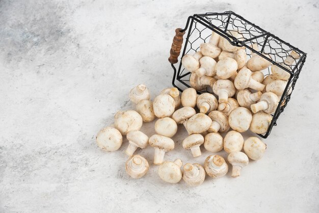 White mushrooms out of a metallic basket.