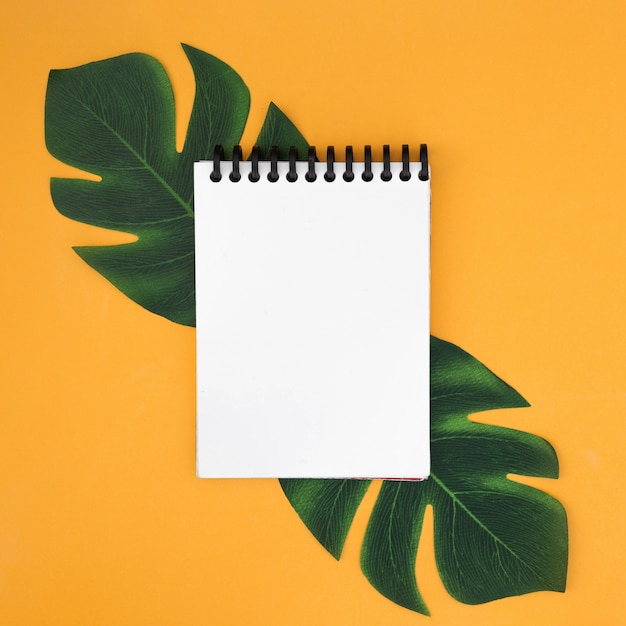 Free photo white notebook with tropical leaves