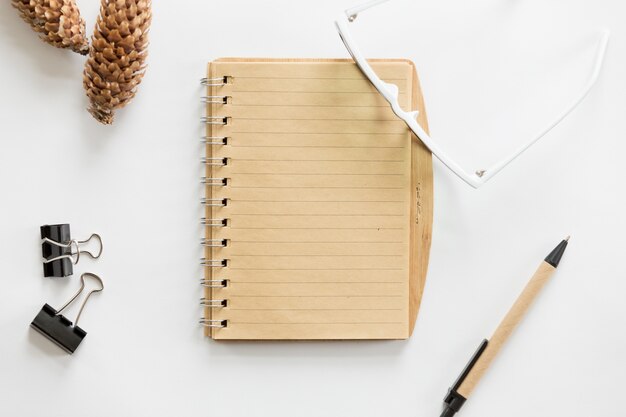 White office desk with glasses, pen, notebook and cone on