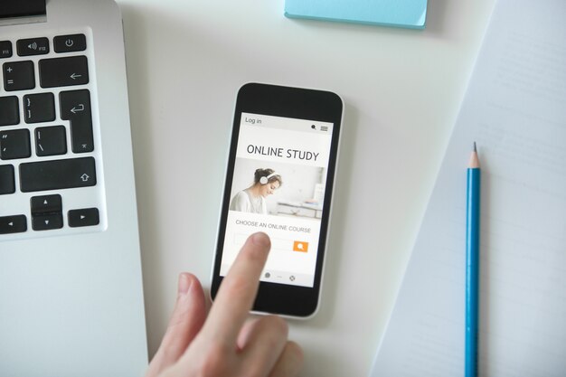 White office desk with a hand touching a mobile phone