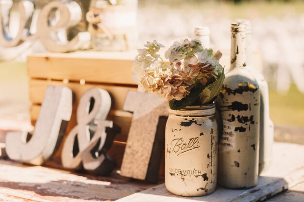 White old bottles with beige flowers stand before wooden 