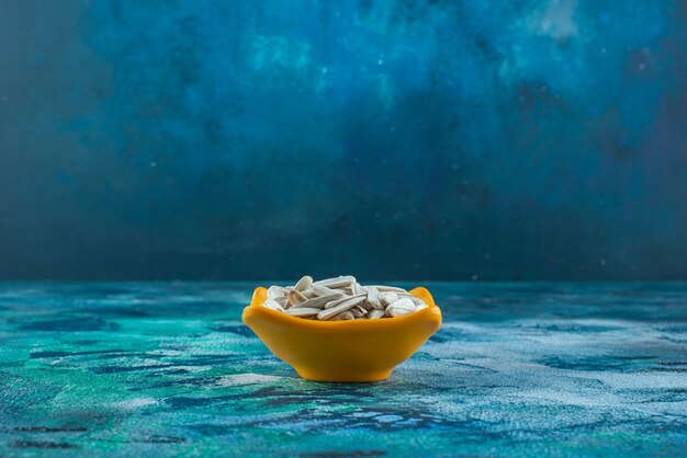 White organic sunflower seed in a bowl on blue. 